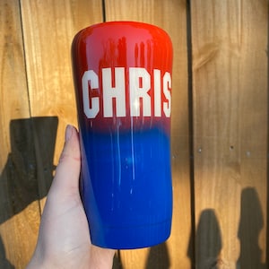 May include: A red and blue ombre tumbler with the name "CHRIS" in white lettering.