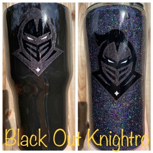 Puede incluir: Dos vasos negros con un dise&ntilde;o de casco de caballero. Un vaso es negro liso, el otro est&aacute; cubierto de purpurina negra. El texto "Black Out Knightro" est&aacute; en la parte inferior de la imagen.
