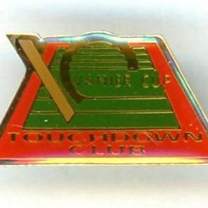 May include: A rectangular pin with a gold border, featuring a red and green design. The pin has the words "VANIER CUP" and "TOUCHDOWN CLUB" in gold lettering. A gold "X" is on the left side.