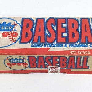 Puede incluir: Una caja de cromos de béisbol Fleer de 1990. La caja rectangular tiene texto rojo y azul que dice "BASEBALL" y "LOGO STICKERS & TRADING CARDS". Contiene 672 cromos y 45 pegatinas.