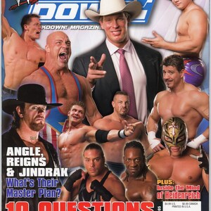 Puede incluir: Una portada de revista de WWE SmackDown! de enero de 2005, con varios luchadores. La portada incluye texto como "ANGLE, REIGNS & JINDRAK" y "10 QUESTIONS". La revista tiene un esquema de color azul y blanco.