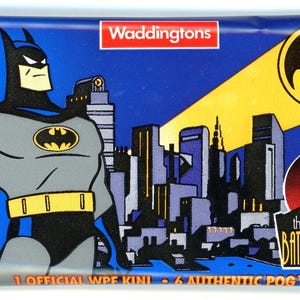May include: A Batman-themed collectible milkcap package. The package features a cartoon image of Batman, the Batman logo, and the text "the adventures of BATMAN & ROBIN". The package also has the text "1 OFFICIAL WPE KINI & 6 AUTHENTIC POG MILKCAPS".
