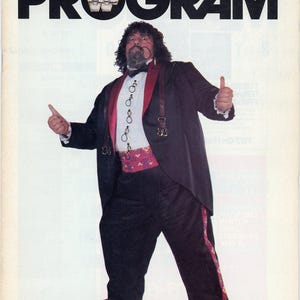 May include: Cover of a World Wrestling Federation program, Volume No. 121. The cover features a man in a tuxedo with a red and purple patterned sash, suspenders, and sneakers. The word "PROGRAM" is in large black letters.