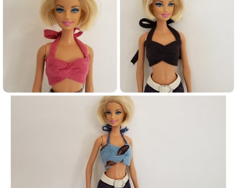 May include: Three Barbie dolls wearing different halter tops. The tops are pink, black, and blue with a brown pattern. The dolls have blonde hair and blue eyes.