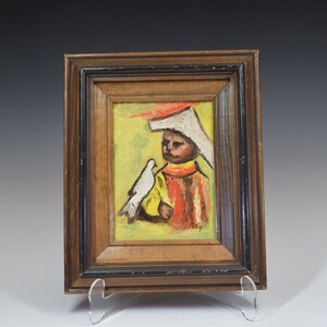May include: A framed oil painting of a person wearing a white hat and red and yellow clothing, holding a white dove. The painting has a yellow, green, and red background.