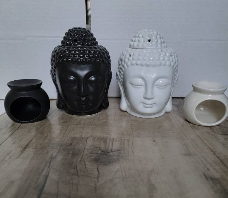 May include: Two ceramic Buddha head oil diffusers, one black and one white, with a small round black and white oil burner on each side.