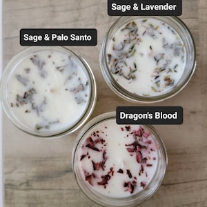 Può includere: Tre barattoli di vetro con candele bianche e diversi ingredienti naturali. Le candele sono etichettate "Salvia e Palo Santo", "Salvia e Lavanda" e "Sangue di Drago".