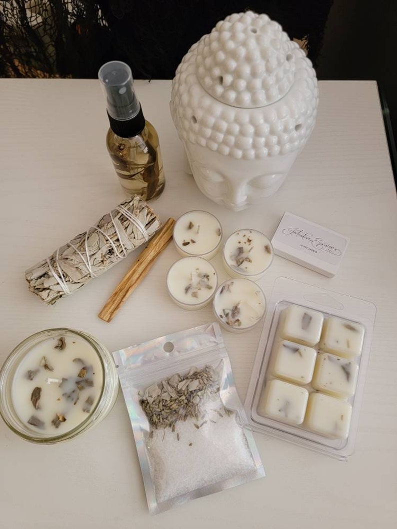 May include: A white ceramic Buddha head diffuser, a white candle, a white wax melt set, a white sage smudge stick, a small bag of white sage and salt, a cinnamon stick, and a bottle of essential oil.