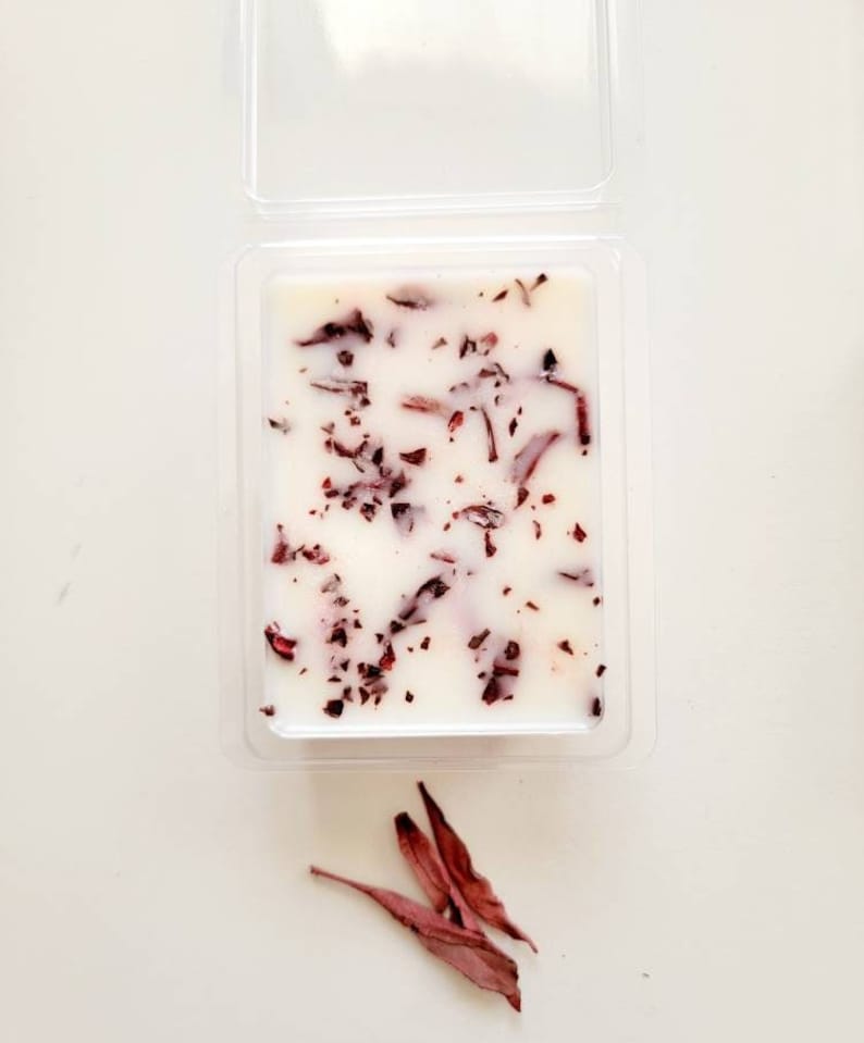 Pu&ograve; includere: Un fondente di cera bianco con petali di fiori rossi incorporati. Il fondente di cera &egrave; in un contenitore di plastica trasparente.