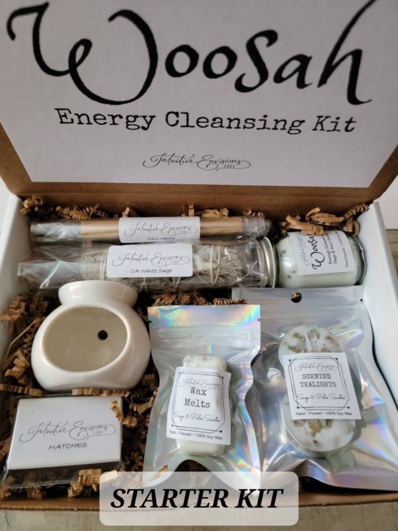May include: A starter kit for energy cleansing with the words "Woosah Energy Cleansing Kit" on the box. The kit includes a white ceramic oil burner, a small box of matches, a bag of wax melts, a bag of scented tealights, a small jar of white sage, and a wooden smudge stick.