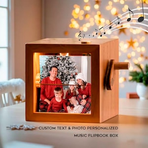 May include: A wooden music flipbook box featuring a family photograph. The box has a crank handle and the text "CUSTOM TEXT & PHOTO PERSONALIZED MUSIC FLIPBOOK BOX" is visible. Musical notes are shown above the box.