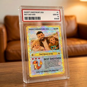 May include: A custom collectible trading card encased in a clear protective slab. The card features a holographic illustration of a father with two children, labeled 'DADDY'S ADVENTURE 2026', 'Dad, Mason & Lily', and 'BEST DAD EVER' with a Charmander graphic.