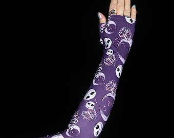 May include: Purple arm warmers with a repeating pattern of white skulls, crescent moons, and skeletal hands.