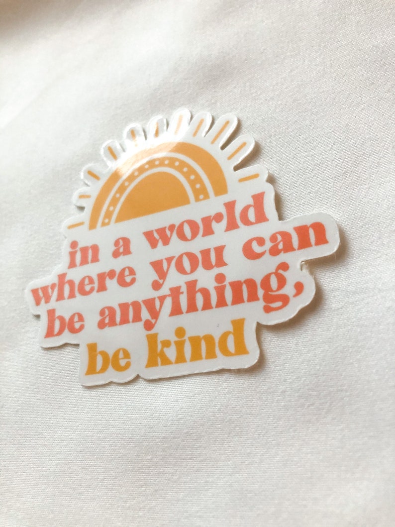 May include: A sticker with a yellow sun and the text "in a world where you can be anything, be kind".