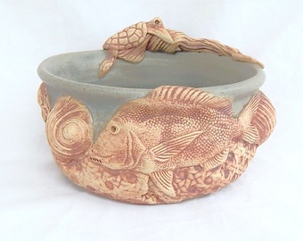 Handcrafted stoneware soup bowl with shells and other sea creatures in matt green glaze.