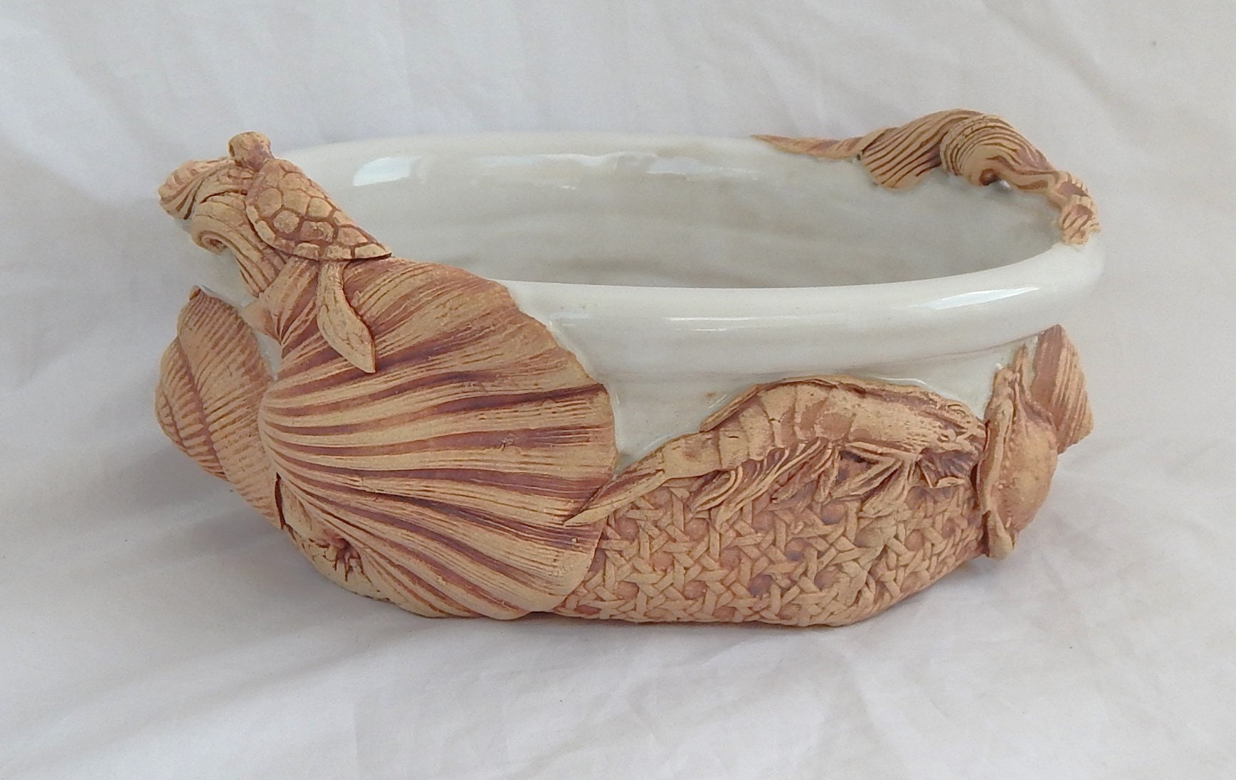 Teglia per brie in gres realizzata a mano, decorata con conchiglie e altre creature marine smaltate di bianco.