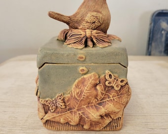 Pequena urna com motivos da natureza, representando pássaros, carvalho, bolotas, borboletas, abelhas e libélulas. Feita à mão em cerâmica.