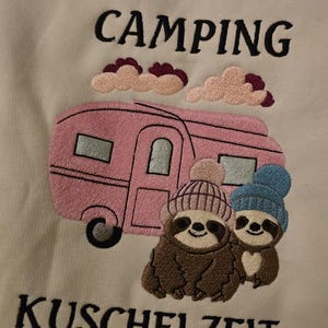 May include: Embroidered design featuring a pink camper, two sloths wearing beanies, and the text "CAMPING KUSCHELZEIT" in black. The design includes pink and maroon clouds.