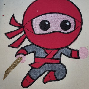 May include: Embroidered design of a red ninja with a black mask, grey clothing, and a gold sword. The ninja is in a running pose with one leg raised.
