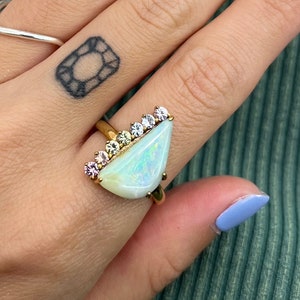 Our 14k gold Australian boulder opal and rainbow sapphire ring. This unique ring features a large,half moon shaped boulder opal with a line of rainbow sapphires along the flat edge.