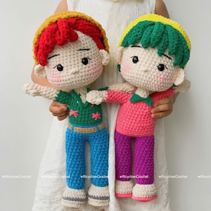 May include: Two handmade crochet dolls, each with a unique outfit. One doll has red hair, a green shirt, blue pants, and a yellow hat. The other doll has green hair, a pink shirt, purple pants, and a yellow hat.