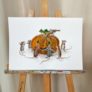 Watercolor painting of little mice dancing around carved pumpkin. Halloween artistic decor with jack-o&#39;-lantern.