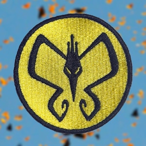 Puede incluir: Parche bordado con un diseño de pájaro estilizado en azul marino sobre un fondo circular amarillo. El parche tiene un borde azul marino. El fondo es un azul borroso con acentos naranjas.