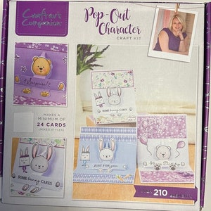 Peut inclure: Une trousse de création au design violet et blanc. La trousse comprend plus de 210 éléments pour réaliser au minimum 24 cartes pop-up. Les cartes ont un thème lapin et ours. Le texte sur la boîte indique "Pop-Out Character Craft Kit".