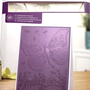 May include: A purple 3D embossing folder by Gemini, with a butterfly design. The card measures 5" x 7" (12.7cm x 17.8cm). The packaging includes text in English, French, Spanish, and German.