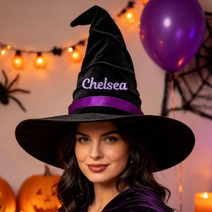 May include: A black velvet witch hat featuring a wide brim and a pointed crown. The hat is accented with a purple satin ribbon band and the name Chelsea embroidered in purple thread on the front of the crown above the ribbon band.