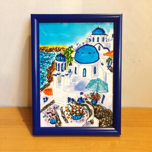Puede incluir: Una pintura enmarcada que representa un edificio blanco con c&uacute;pulas azules, sobre un fondo de cielo azul y oc&eacute;ano. El edificio est&aacute; rodeado de flores y una sombrilla azul.