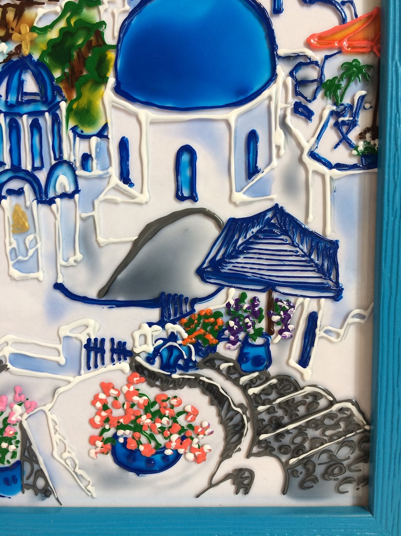 Puede incluir: Una obra de arte de vidrio pintado que representa un edificio blanco con una c&uacute;pula azul, rodeado de flores y un camino de piedra gris. La obra est&aacute; enmarcada en un marco azul.