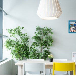 Puede incluir: Una mesa de comedor blanca con cuatro sillas, dos blancas y dos amarillas. Hay dos plantas en macetas, un cuadro enmarcado de un pueblo griego y un cartel con el texto "Lemonade" en la mesa. La habitaci&oacute;n tiene una ventana grande y una l&aacute;mpara de techo blanca.