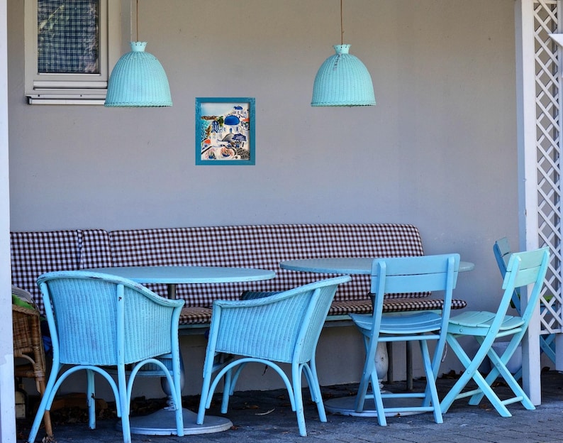 Puede incluir: Un banco de cuadros azules y blancos con cuatro sillas azules y una mesa azul. Dos l&aacute;mparas colgantes azules cuelgan sobre la mesa. Un cuadro enmarcado de una escena de playa cuelga en la pared.