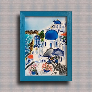 Puede incluir: Una pintura enmarcada de un pueblo griego blanco y azul con una iglesia de c&uacute;pula azul, con vistas a un mar azul. La pintura est&aacute; enmarcada en un marco azul turquesa.