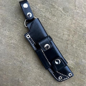 May include: A black leather knife sheath with a belt loop and snap closure. The sheath has white stitching and silver rivets.