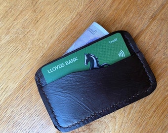 May include: A brown leather wallet with a green Lloyds Bank credit card inside. The card has a horse logo and the word "Credit" printed on it.