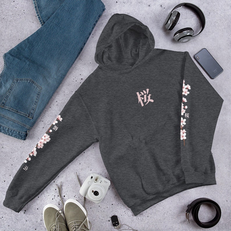 May include: A dark gray hooded sweatshirt with a pink Japanese character on the front and a pink floral design on the sleeves. The character is "桜" which means "cherry blossom".