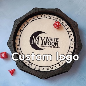 May include: A black octagonal dice tray with a white interior featuring the "My White Moon handmade studio" logo and the words "Custom logo". Three red dice are scattered around the tray.