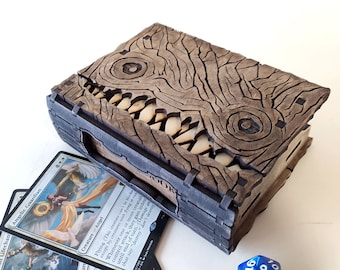 May include: A wooden box with a carved monster face on the lid. The box is open and has a few playing cards inside. The box is a great way to store and display your favorite playing cards.