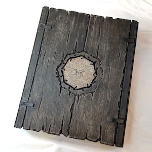 May include: A dark wooden box with a metal skull and crossbones design on the front. The box has metal hinges and clasps.