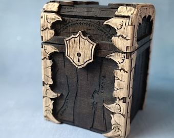 May include: A wooden treasure chest with a dark brown finish and light brown accents. The chest features intricate carvings, including corner details and a shield-shaped lock. The overall design suggests a vintage or fantasy theme.