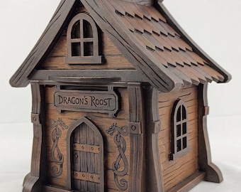 May include: A brown wooden model house featuring a gabled roof with shingle details, an arched door, and two arched windows. The front facade displays a sign with the text "DRAGON'S ROOST" and engraved dragon motifs on either side of the door.