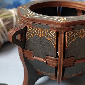 Handmade gothic wooden cauldron storage box, ideal for Wiccan altar decor, witchy jewelry organizer, and spell jar storage, enchanted fantasy trinket holder with mystical engravings, aged distressed wood design, perfect Halloween decor for witches and pagans, dark academia aesthetic altar accessory, handcrafted rustic potion holder, mystical gothic-inspired gift, spiritual home decor piece, unique magic ritual storage, fantasy home accent for gothic and occult lovers
