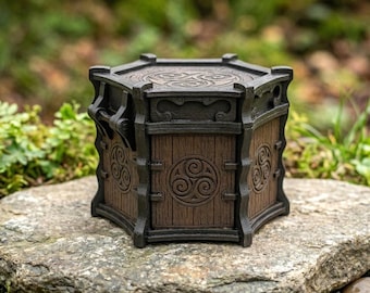 May include: A hexagonal box with a dark brown wood-grain finish and black structural framing. Each side panel features a circular triskelion emblem. The lid is also hexagonal with a matching triskelion design centered on the top surface.