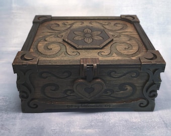 May include: A wooden box with intricate floral and scrollwork carvings. The box is stained in shades of brown and features a heart-shaped clasp. The top has a flower design in the center. The text "my littlesecrets" is visible on the bottom.