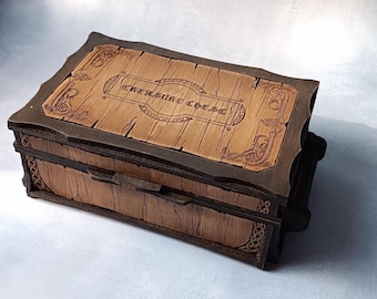 May include: A wooden treasure chest with a dark brown frame and a light brown lid. The lid is engraved with the words "TREASURE CHEST" and decorative patterns. The chest has a rectangular shape and a hinged lid.