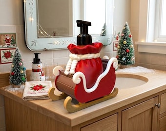 Könnte beinhalten: Ein rot-brauner Seifenspender in Form eines Geschenkesacks vom Weihnachtsmann, der in einem dekorativen Schlitten steht. Der Spender verfügt über einen schwarzen Pumpmechanismus, ein weißes Seil als Verschluss und weiße, geschwungene Kufen.