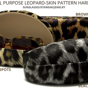 May include: Three hard shell cases for sunglasses, eyewear, or jewelry. The cases are made of a leopard-skin pattern material. The top case is brown with gold spots, the middle case is black with gold spots, and the bottom case is black with white spots. The text "DESIGNER ALL PURPOSE LEOPARD-SKIN PATTERN HARD SHELL CASES" is at the top of the image. The text "SUNGLASSES/EYEWEAR/JEWELRY" is below the first line of text. The text "BROWN & GOLD SPOTS" is above the top case. The text "BLACK & GOLD SPOTS" is below the middle case. The text "BLACK & WHITE SPOTS" is below the bottom case.