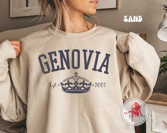 Może przedstawiać: Beżowa bluza z napisem "GENOVIA" w granatowych, blokowych literach. Poniżej granatowy wzór korony z napisem "Est. 2001". Bluza ma okrągły dekolt.